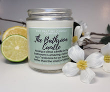 Load image into Gallery viewer, The Bathroom candle by the Saltine Candle company is surrounded by a fresh lime cut in half and a fresh lemon. On the other side are white yuzu flowers.
