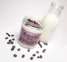 Load image into Gallery viewer, The Work From Home Candle is on a white background surrounding by fresh coffee beans and a glass container of cream.
